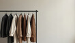 © Maryna - Collection of neutral colored blazers and jackets hang on a black rack. Minimalist fashion boutique interior with blank wall. Clean modern clothing store.