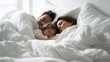 © Broccolini - A heartwarming lifestyle portrait of a young family with a small child sleeping peacefully together in a large, comfortable bed with soft white linens in a bright bedroom.