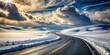 © Collection - A winding asphalt road through a snow-covered landscape under a dramatic sky with bright sun rays piercing through heavy clouds