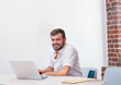 © wavebreak3 - Male wearing short-sleeve white shirt working on silver laptop in bright office with manila folder
