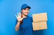 © luismolinero - Delivery girl over isolated blue wall counting five with fingers
