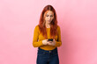 © luismolinero - Teenager Russian girl isolated on pink background sending a message with the mobile