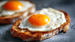© Sabana - Two slices of toasted bread topped with sunny side up eggs on a gray surface