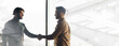 © Prostock-studio - Two men stand in a modern office setting. They are shaking hands. Large windows let in natural light. The room has a clean and minimalist look. It seems to be a positive business meeting.