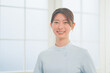 © HML - 明るく清潔感のあるクリニックでにこやかに笑う20代女性看護師