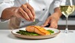 © Mamad - Chef garnishing a delicious salmon fillet with herbs, served with asparagus