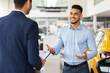 © Prostock-studio - Rich handsome middle-eastern young man visiting newest auto showroom or dealership salon, buying auto, talking to sales manager and smiling, asking for help with choosing nice automobile