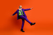© deagreez - Old man in purple suit green shirt and sunglass dancing joyfully against bright orange studio background