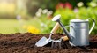 © RIDOY - Gardening tools including a metal watering can, hand trowel, and rake on fertile brown soil in a sunny garden with blurred flowers