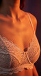 © Inspire Shots Hub - Close-up of woman's torso wearing white lace bra, illuminated by warm orange light, creating a soft, sensual texture and mood, ideal for fashion or lingerie advertisement