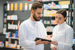 © Serhii - Pharmacists discussing medication using tablet in pharmacy
