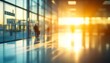 © V Art - Sunset light streaming through large windows illuminating a modern interior space with silhouettes of people in an airport terminal
