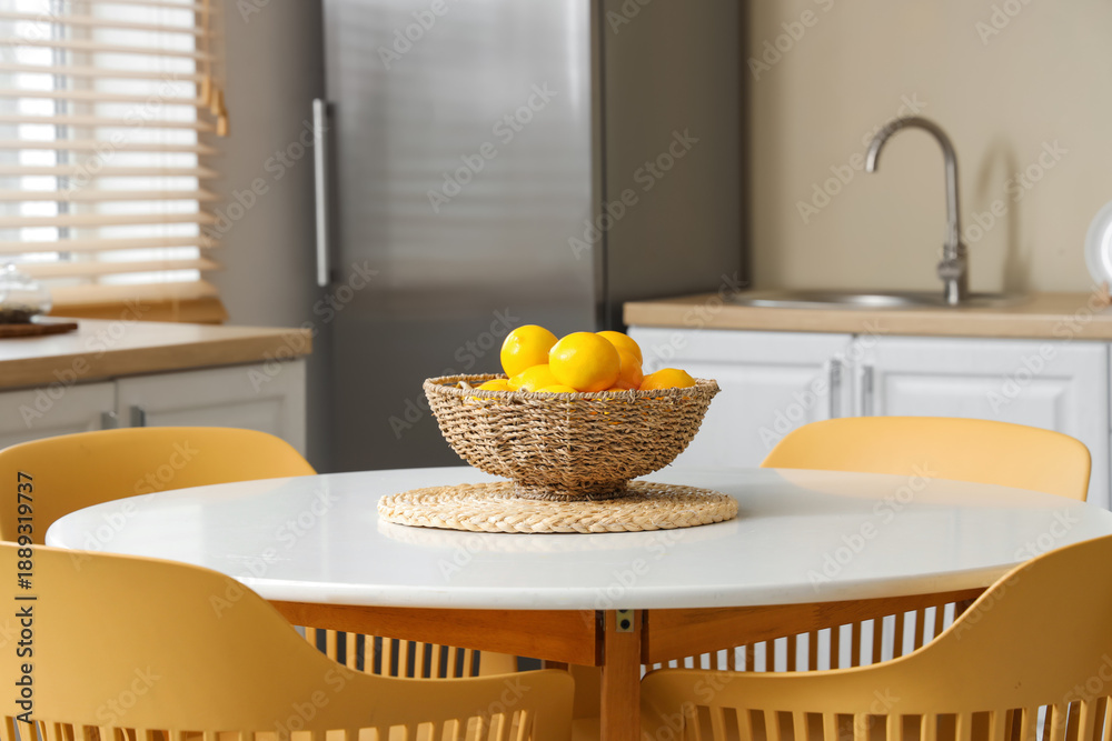 Wicker bowl with lemons on dining table in kitchen