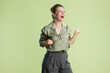 © Alliance - A woman in green celebrates with fists pumping, eyes closed in joyful expression.  A powerful image of achievement and positive emotion against a light green backdrop.