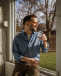 © Miljan Živković - Happy man in casual wear drinking water at window