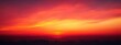 © tiger - Vibrant orange and red sunset sky with layered clouds creating a serene and warm atmosphere over a dark horizon