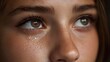 © Bussakon - A single tear glistens on a person s cheek as they look upwards with expressive brown eyes