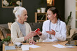 © AnnaStills - Senior Caucasian woman receiving prescription medication from young adult Caucasian female doctor sitting at desk, discussing treatment options and healthcare instructions together