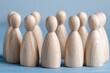 © pattaphorn - Wooden Figurines Representing Unity and Collaboration in a Circle Arrangement on a Light Blue Background