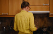 © M-Production - Woman in yellow shirt cooking in kitchen.