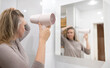 © M-Production - Woman drying her hair with hair dryer.
