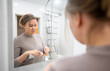 © M-Production - Woman putting toothpaste on brush in bathroom.