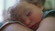 © Marco - Close up of sleeping toddler breastfeeding with face resting peacefully on mother’s chest, capturing tender intimacy and emotional connection indoors