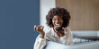 © Moon Safari - Portrait of cheerful businesswoman with afro hairstyle talking on mobile speaker while relaxing on sofa in office