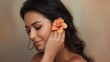 © Future Vision - Smiling woman tilting head, looking down in studio holding orange hibiscus at ear, in strapless top