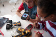 © Halfpoint - High school students working on robotics project, using online AI app to answer questions.