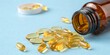 © Anee - Amber supplement bottle tips over as yellow capsules rest on clean blue background with copy space for wellness advertising