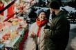 © BGStock72 - Korean woman and Caucasian man enjoy treats at winter market in snowy setting