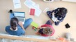 © DawDunia - Mother working on laptop from home while two young children play and read nearby, capturing the juggle of remote work, parenting and everyday family life in a busy living room