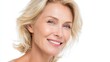 © mila103 - A middle-aged woman with blonde hair smiles warmly while highlighting her natural beauty. Soft lighting enhances her features creating a joyful and inviting atmosphere.