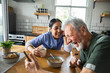 © Marko Geber - Caregiver and senior man laughing over breakfast at home