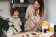 © verona_studio - Mom and child bake together in the kitchen while having fun with dough and jam at home in the morning light