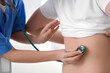 © Pixel-Shot - Female doctor with stethoscope listening to male patient in clinic, back view