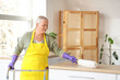 © Pixel-Shot - Mature woman with walker and pp-duster cleaning table in kitchen