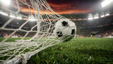 Action shot of soccer ball hitting the net with flying grass particles and stadium lights background. Goal and victory concept.