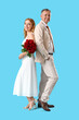 © Pixel-Shot - Happy mature couple with bouquet of roses on blue background. Valentine's Day celebration