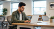 © BornHappy - Focused male entrepreneur sitting at a wooden desk typing on a laptop keyboard in a spacious coworking environment with large windows