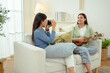 © tonefotografia - Happy Girls Enjoy Time Together on a Cozy Sofa While Playing Music in a Bright Living Room