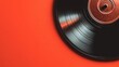 © PengAI - A close-up of a black vinyl record resting on a vibrant red surface, showcasing the record's grooves and central spindle.