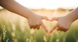 © antuanetto - Two children's hands joyfully forming a heart shape against a golden sunset, representing profound love, family bonding, and a hopeful future concept