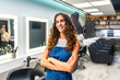 © unai - Confident female hairstylist smiling in hair salon