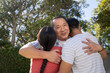 © wavebreak3 - Asian family embracing each other in suburban backyard garden by fence and trimmed hedge
