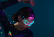 © VISTA by Westend61 - Woman with glowing virtual reality glasses indoors in futuristic light