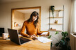 © Jordi Salas - Woman managing invoices and finances at home office using laptop