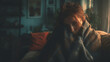 © Sadia - Red-haired woman curled up on sofa under a blanket, looking sad and pensive in dim light