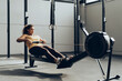 © Westend61 - Young woman exercising in gym with rowing machine